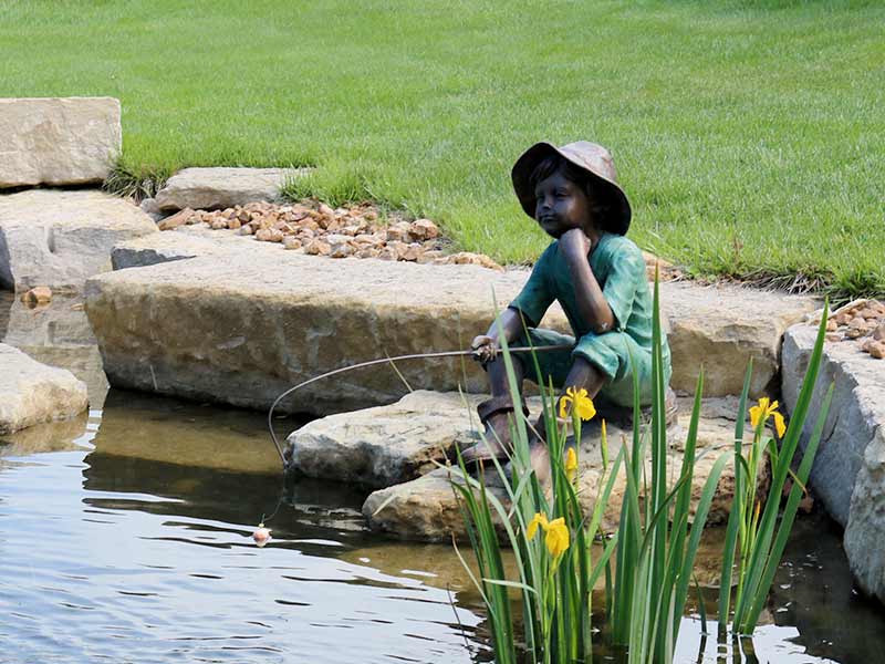 Beautifully landscaped pond with a bronze statue and fountain in the yard of a Bridge Home residence